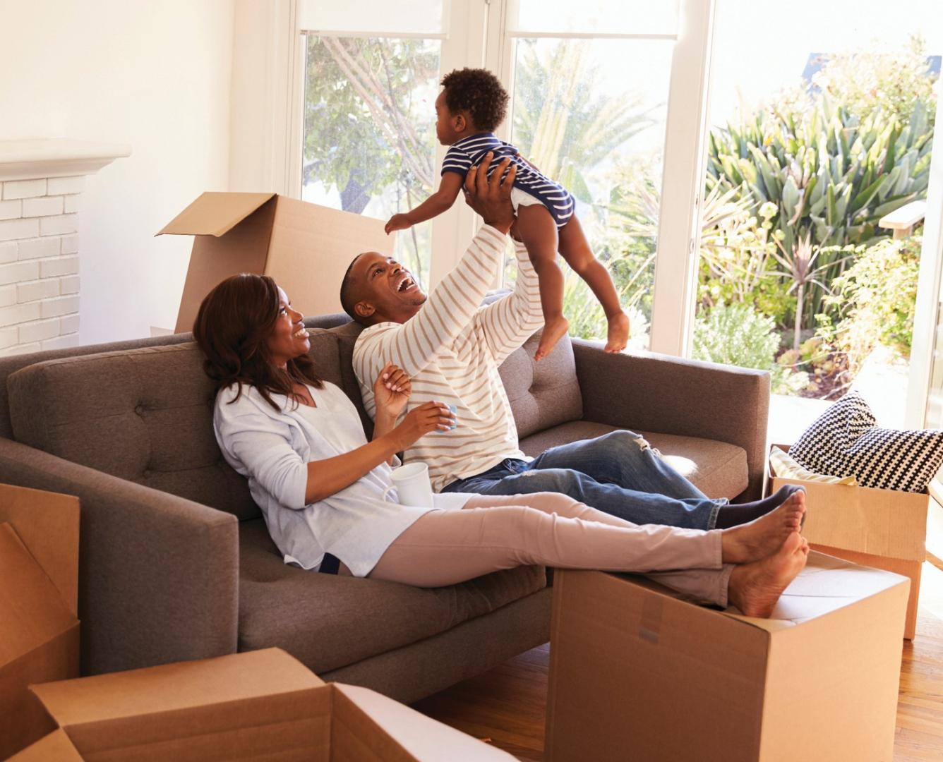 A mother, father, and child playing while moving into their new place